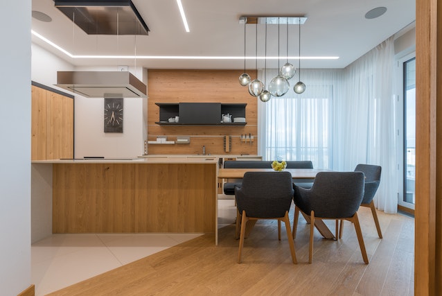 kitchen with wooden island and cabinets and four blue chairs around a table